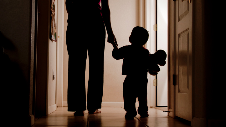 nighttime potty training and bedwetting, little child walking down the hall in the dark with a parent and a stuffed animal