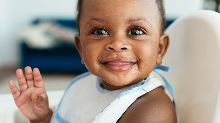 baby in high chair looking at food, nutritional needs of babies
