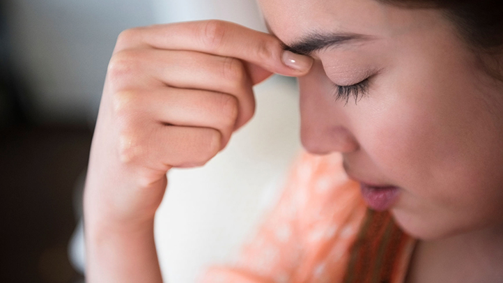 postpartum preeclampsia, woman with headache touching her forehead