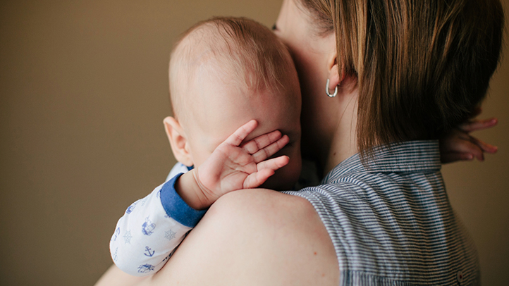 rsv in babies, sick baby with hand over his eyes being held by mom