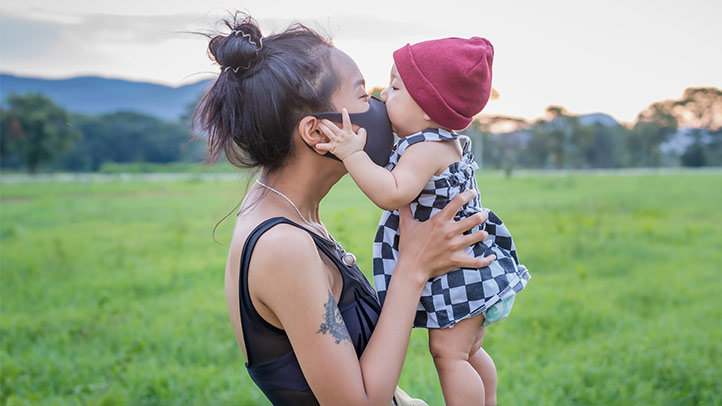 covid-19 vaccine kids under 5 coming soon, should you vaccinate your baby or toddler against covid-19, mother in mask with baby kissing face in a field