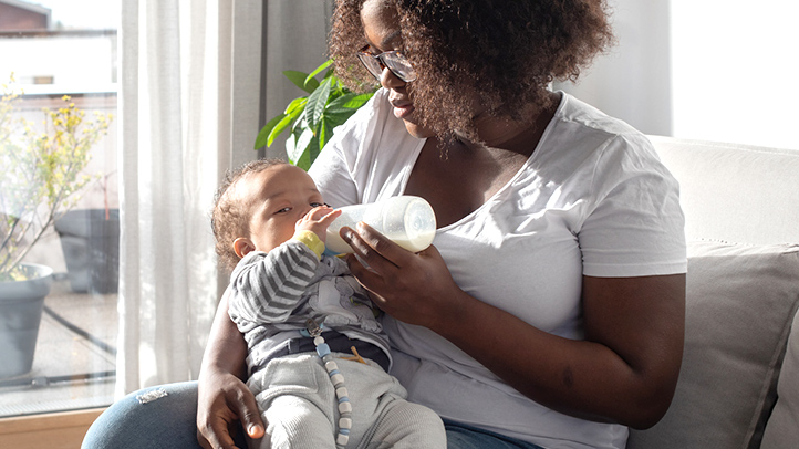 mom helping baby hold a bottle