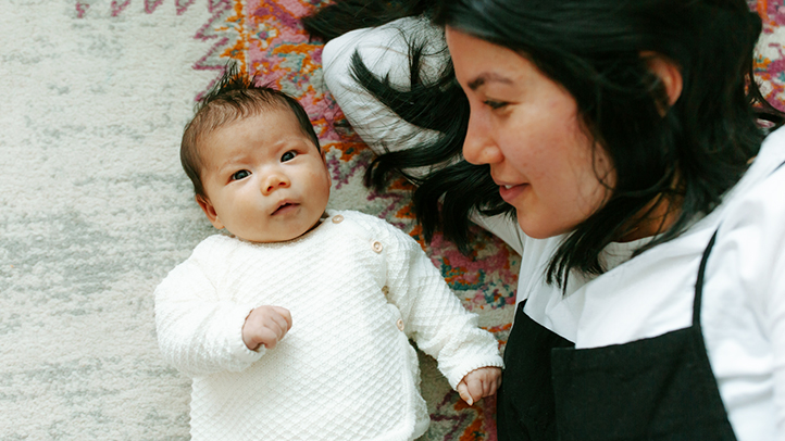 when to stop swaddling baby, young baby lying down with mom